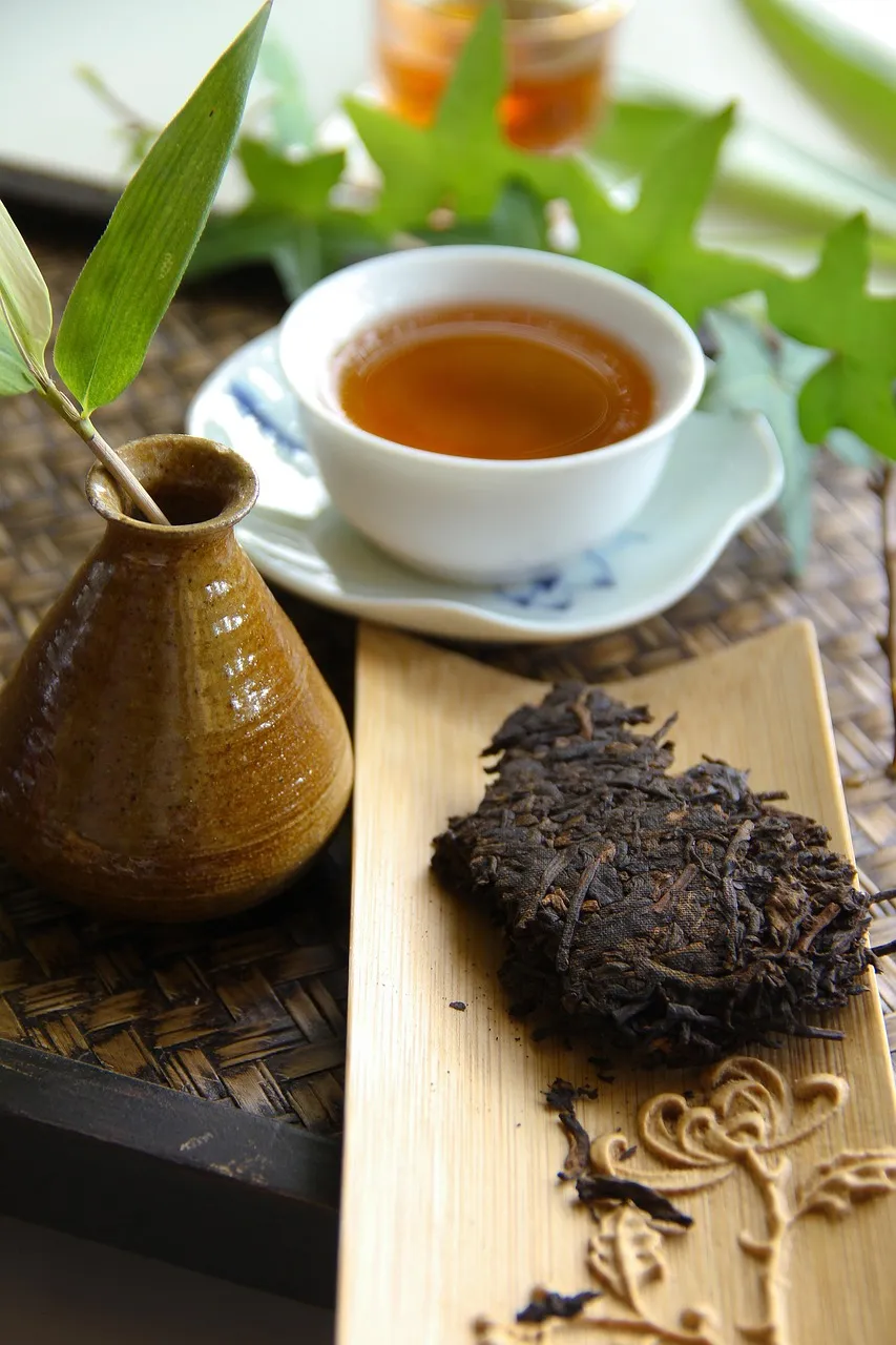 En bit pressad pu-erh-kaka bredvid en kopp mörkt te